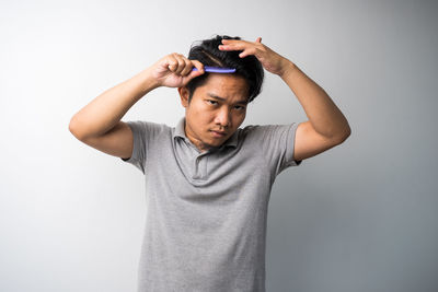 Portrait of young man with arms outstretched against white background