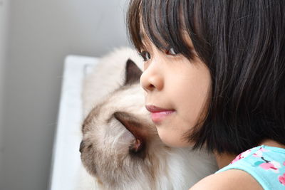 Close-up of girl with cat looking away at home