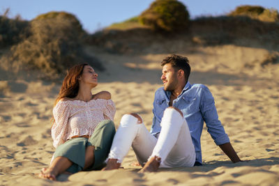 Full length of couple sitting on sand