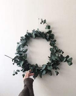 Cropped image of woman touching wreath at wall