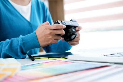 Midsection of woman holding camera in office