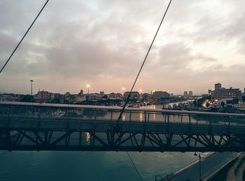 Bridge over river against cloudy sky