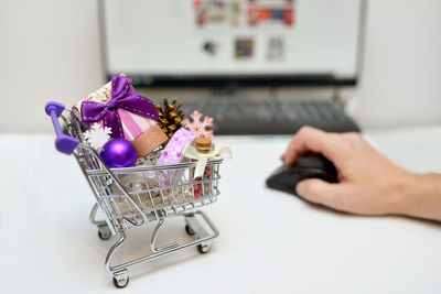 Cropped hand using computer by gifts at desk