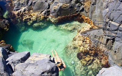 High angle view of woman swimming in sea amidst rocks