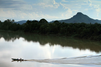 Scenic view of river by trees against sky