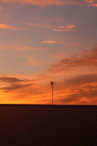 Low angle view of silhouette roof against sky during sunset