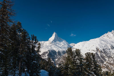 Scenic view of snowcapped mountains against blue sky