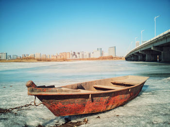 Boats moored on shore against clear sky