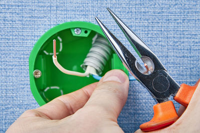 Cropped hands cutting wire of electrical outlet