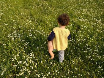 Rear view of boy with toy walking on grassy field