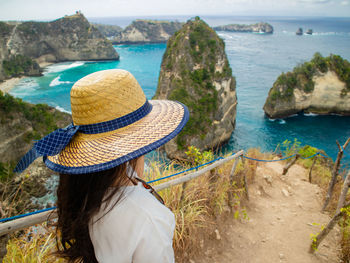 Woman standing by railing while looking at sea