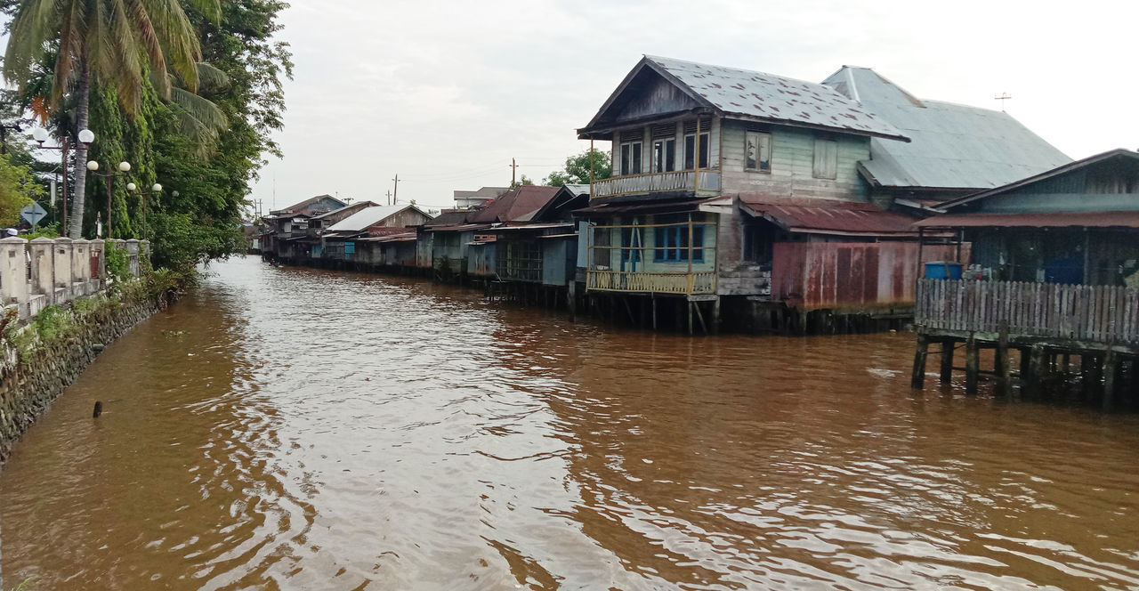 water, architecture, built structure, building exterior, building, house, nature, stilt house, residential district, river, sky, event, flood, no people, travel destinations, outdoors, wood, tourism, waterway, city, environment, tradition, day, tropical climate, travel, cloud, nautical vessel, village, tree
