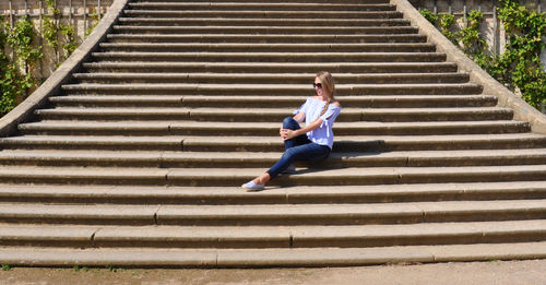 Full length of woman sitting on staircase