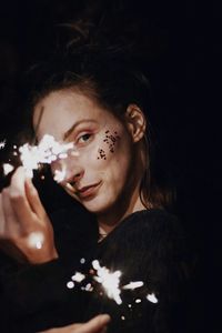 Close-up portrait of beautiful woman against black background