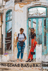 Portrait of smiling young woman standing against building