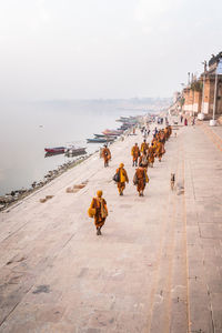 People walking by sea against sky in city