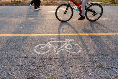 Low section of man riding bicycle by sign on road