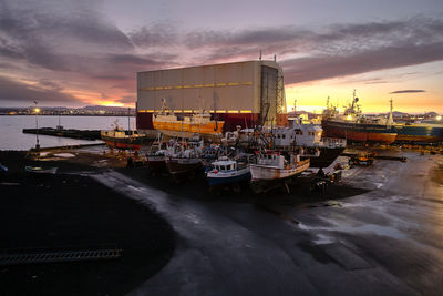 Boats moored at harbor against sky during sunset