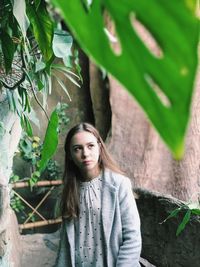 Portrait of young woman standing against plants