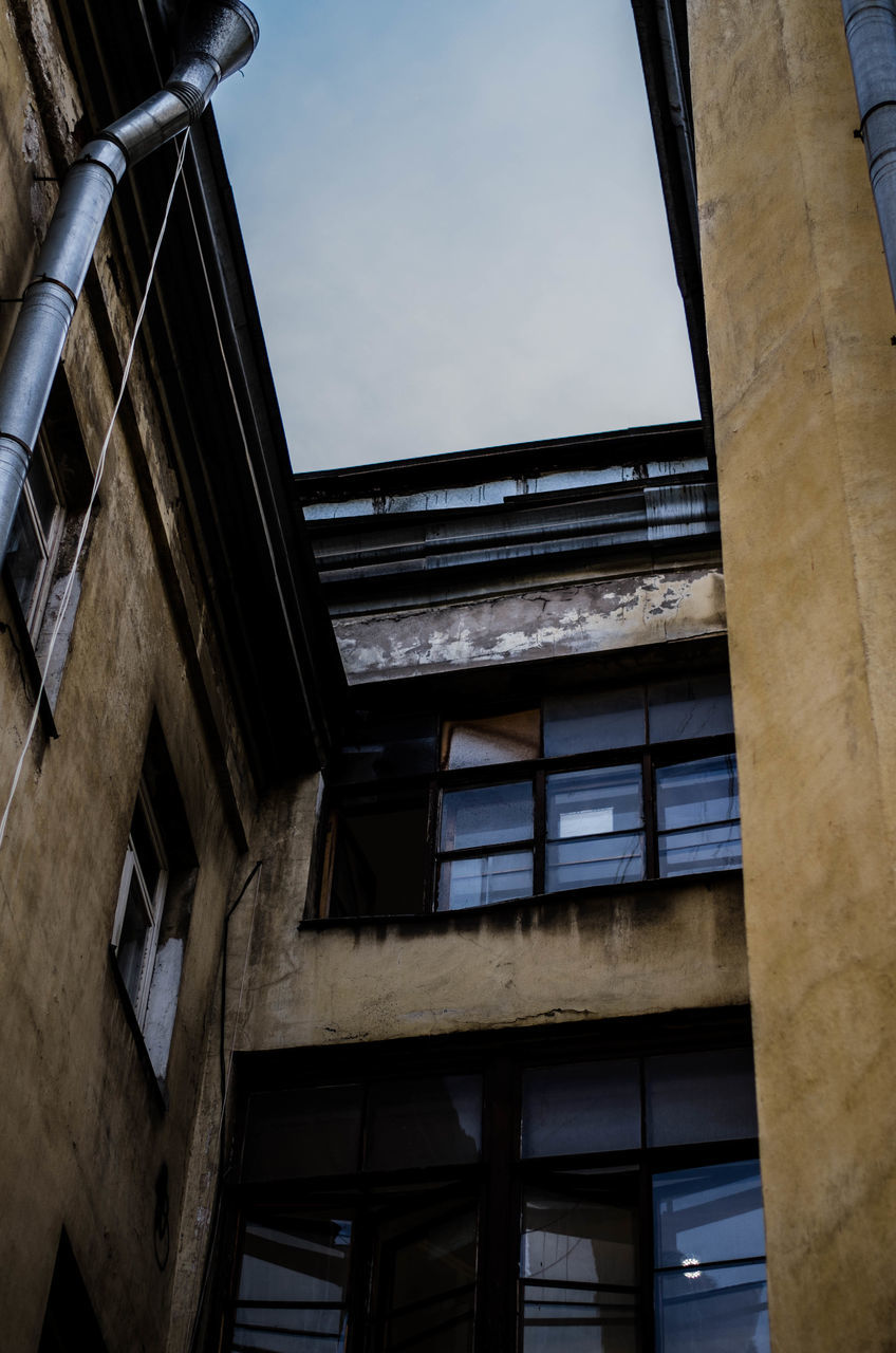 architecture, built structure, building exterior, low angle view, window, building, sky, residential building, residential structure, city, glass - material, day, no people, outdoors, old, exterior, clear sky, architectural column, balcony, sunlight