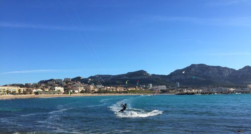 Man kiteboarding at sea against blue sky