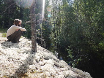 Side view full length of man crouching at forest