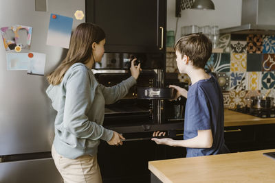 Side view of smiling young woman looking at table at home