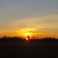 Scenic view of silhouette field against sky during sunset