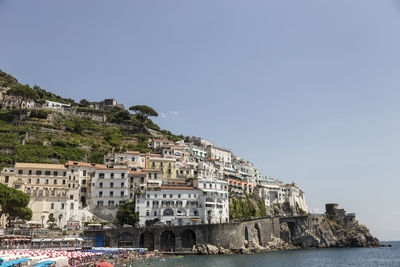 Buildings by sea against clear sky