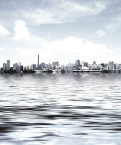 Scenic view of river by cityscape against sky