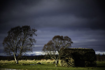 Leanach cottage on field against cloudy sky at scottish highlands