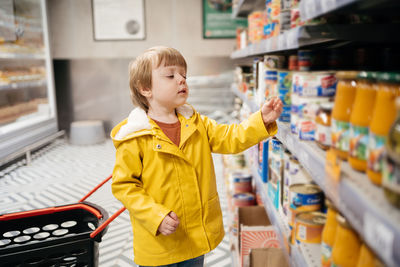 Child in the market with a grocery cart, chooses a product