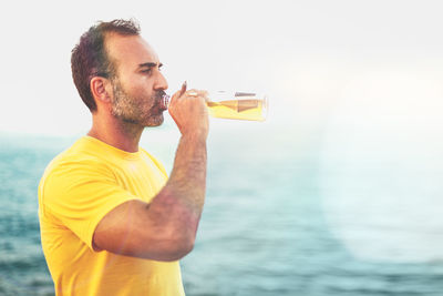 Midsection of man drinking glass against sea