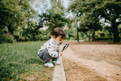 Full length of boy using magnifying glass outdoors