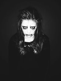 Portrait of teenage girl in halloween make-up against black background