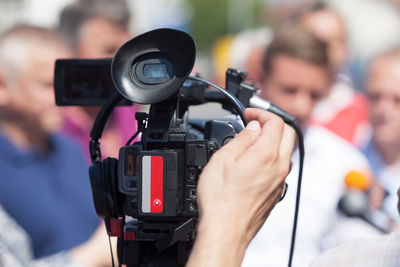 Cropped hand of man on video camera