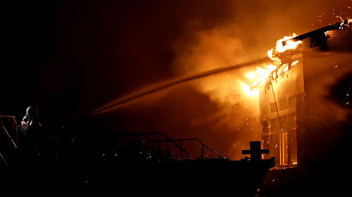 Firefighter throwing water on fire at building