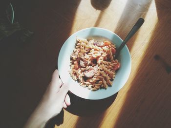 Close up of hand holding plate with pasta in sunlight