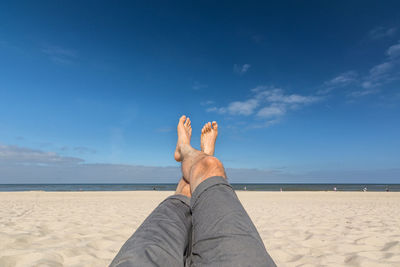 Low section of man relaxing at beach