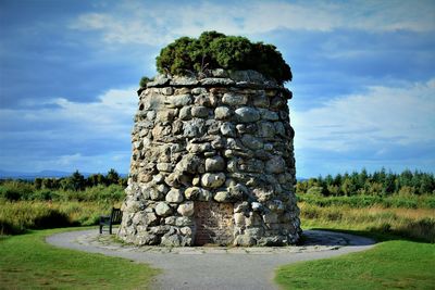 Old stone wall on field against sky