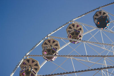 Low angle view of ferris wheel against clear blue sky