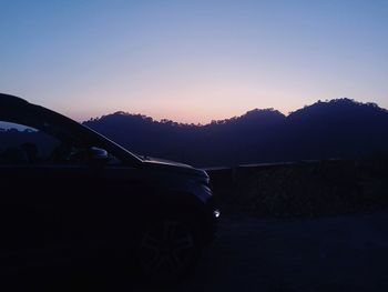 Car on road against clear sky during sunset