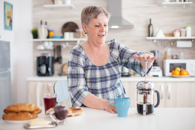 Senior woman making coffee at home