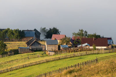 Houses by agricultural field against sky