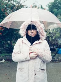 Midsection of woman holding umbrella while standing outdoors during rainy season