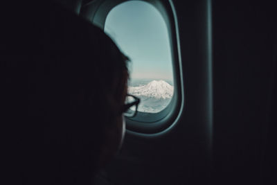 Cropped image of child looking through airplane window
