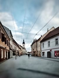 Man walking on street amidst buildings in city against sky