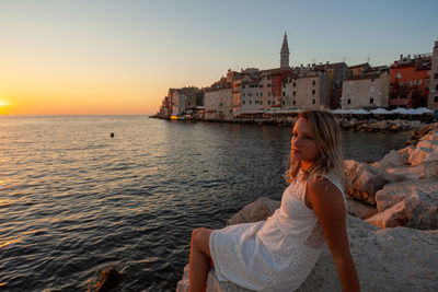 Woman on beach against sky during sunset