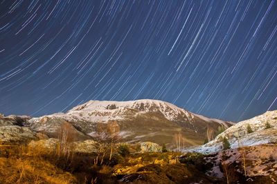 Scenic view of snow covered mountains against star trails