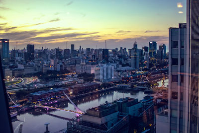 High angle view of illuminated city buildings against sky during sunset